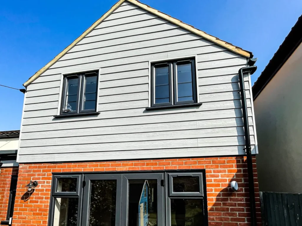 Double storey extension with external cladding and brickwork and black frame windows. 