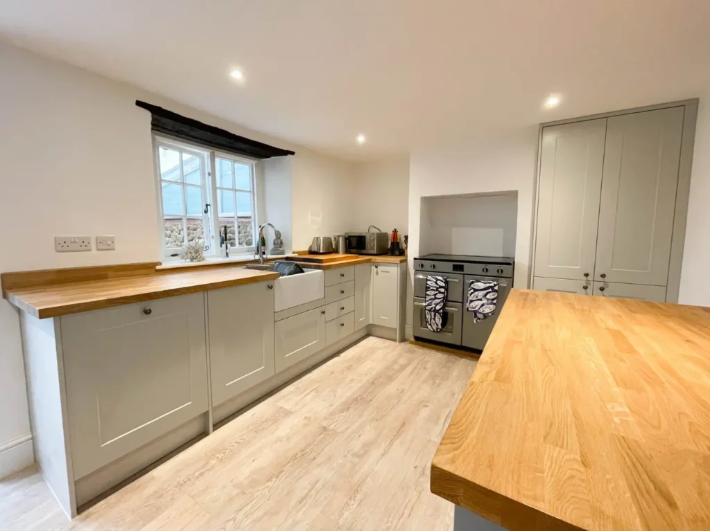 Homely kitchen with green painted kitchen units and wooden features. 