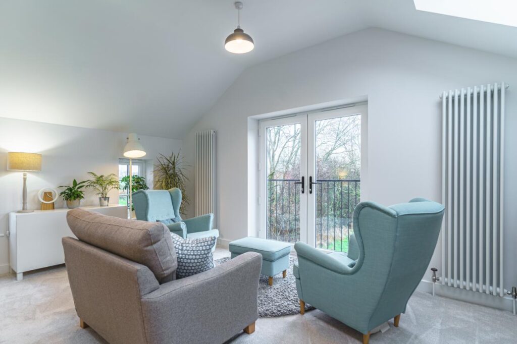 Interior of a double-storey extension, showing a seating area by the top floor window. 