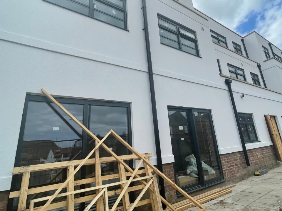 The front of a commercial building with wooden building materials stacked against it. 